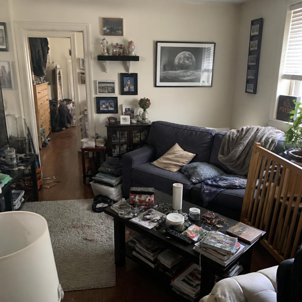 A cramped small living room with crowded surfaces and blocked walking space